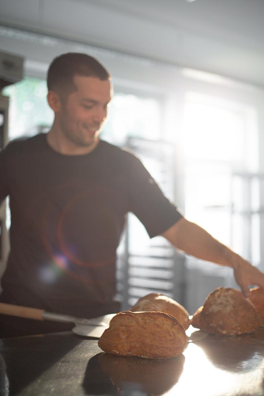 Nick Mikheev smiling with freshly baked artisan bread
